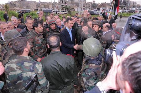 Syria's President Bashar al-Assad (C) shakes hands with a soldier during a tour in the Baba Amr neighbourhood of Homs in this handout photograph released by Syria's national news agency SANA on March 27, 2012. REUTERS/SANA/Handout