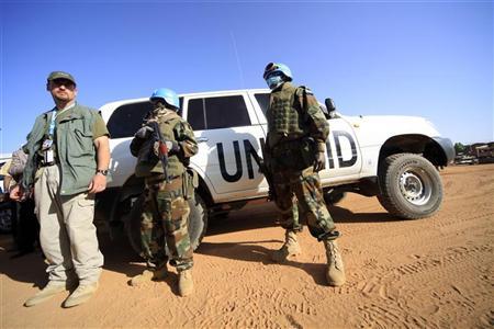 Peacekeepers stand guard near the vehicles of the U.N. delegation after their meeting was disrupted by a group of protesters at the U.N. Compound in Nayala, South Darfur November 30, 2010. REUTERS/Mohamed Nureldin Abdallah