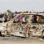 A crowd gathers near a car damaged by an explosion at St. Theresa Catholic Church at Madalla, Suleja, just outside Nigeria's capital Abuja, December 25, 2011. REUTERS/Afolabi Sotunde