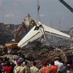 People watch as a crane lifts the tail of a plane after it crashed in Lagos June 4, 2012.REUTERS/Akintunde Akinleye