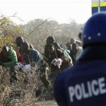 A policeman (R) fires at protesting miners outside a South African mine in Rustenburg, 100 km (62 miles) northwest of Johannesburg, August 16, 2012. REUTERS/Siphiwe Sibeko