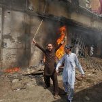 A protester holds a stick as he shouts anti-American slogans in front of a burning cinema during an anti-U.S. protest rally to mark the "Day of Love" in Peshawar September 21, 2012. Demonstrators clashed with police in the Pakistani city of Peshawar on Friday as anger over insults to the Prophet Mohammad boiled over despite calls from political and religious leaders across the Muslim world for peaceful protest. REUTERS/Fayaz Aziz