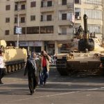 Supporters of the Muslim Brotherhood walk past tanks that were just deployed outside the Egyptian presidential palace in Cairo December 6, 2012. At least three tanks are deployed outside the palace on Thursday in a street where supporters and opponents of President Mohamed Mursi had been clashing into the early hours of the morning, a Reuters witness said. REUTERS/Asmaa Waguih