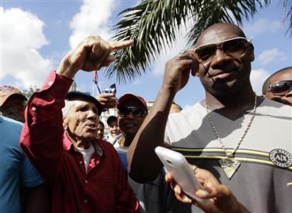 Cuban pitcher Jose Contreras (R) meets fans in Havana January 29, 2013. A decade after he defected to the United States to play Major League Baseball, Contreras has returned to his homeland in the first test of the island's liberalized travel laws. He was welcomed on Tuesday at Havana's Hot Corner, a mecca for baseball fans, by about 200 people who crowded around to get photos and autographs from the lanky right-hander. REUTERS/Desmond Boylan