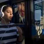 A woman jogs past a vandalized election campaign billboard of Israeli Prime Minister and Likud Party leader Benjamin Netanyahu that is reflected on a bus window in Tel Aviv, Israel, Monday, Jan. 21, 2013. The general elections will be held on Tuesday, Jan. 22, 2013. (AP Photo/Ariel Schalit)