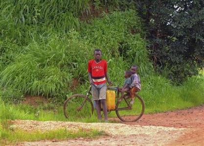 Children are seen with a bicycle on the road outside the village of Tenke, in Congo's copper-producing south, near a smaller hamlet built by the Tenke Fungurume mining operation to rehouse local families displaced by the mine's expansion, January 30, 2013. Katanga, a province roughly the size of Spain, was the heart of central Africa's colonial mining industry, its growth fuelled by Belgium's Union Miniere du Haut Katanga, which produced tonne upon tonne of copper and also the uranium for the atomic bombs dropped on Japan in 1945. Decades of corruption and a brutal civil war brought Katanga to its knees. A period of relative stability since the 2003 peace deal and elections that followed - combined with high metal prices - brought private miners, and officials say Congo's copper exports jumped to 600,000 tonnes in 2012, from under 20,000 a decade ago. Picture taken January 30, 2013. REUTERS/Jonny Hogg