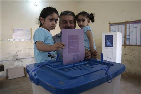 A man holds his daughters as he casts his ballot during the country's provincial elections at a polling station in Basra, 420 km (261 miles) southeast of Baghdad, April 20, 2013. REUTERS/Atef Hassan