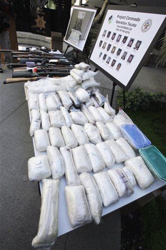 FILE - In this Oct. 22, 2009 file photo, weapons and drugs seized in special joint operation conducted with the Drug Enforecement Administration against the La Familia drug cartel based out of Michoacan, Mexico and operating in San Bernardino and surrounding counties, are on display at a news conference at sheriff's headquarters in San Bernardino, Calif. Drug cartels have long been the nations No. 1 supplier of illegal drugs, but in the past, their operatives rarely ventured beyond the border. A wide-ranging Associated Press review of federal court cases and government drug-enforcement data, plus interviews with many top law enforcement officials, indicate the groups have begun deploying agents from their inner circles to the U.S. (AP Photo/Reed Saxon, File)