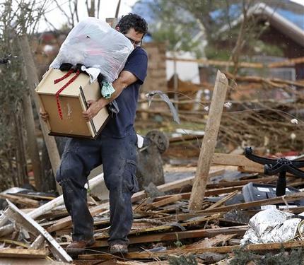 A man carries a drawer and a bag filled with clothes from Rachel Hernandez' home as residents of the Heatherwood Addition, on the south side of SE 4 and Bryant in Moore, Okla.,  returned to their homes Tuesday, May 21, 2013, to salvage any items after Monday's destructive tornado. (AP Photo/The Oklahoman, Jim Beckel)