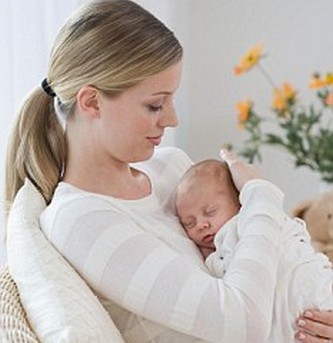 Mother rocking newborn baby in chair