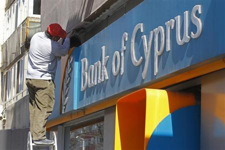 A worker paints a wall above a branch of Bank of Cyprus in Bucharest April 1, 2013. REUTERS/Bogdan Cristel