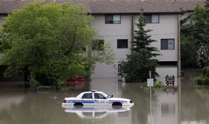 A police car sits stuck in a parking lot of an apartment building after heavy rains have caused flooding, closed roads, and forced evacuation in Calgary, Alberta, Canada Friday, June 21, 2013.  (AP Photo/The Canadian Press, Jeff McIntosh)