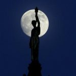 The moon in its waxing gibbous stage shines behind a statue entitled "Enlightenment Giving Power" by John Gelert, which sits at the top of the dome of the Bergen County Courthouse in Hackensack, N.J., Friday, June 21, 2013. The moon, which will reach its full stage on Sunday, is expected to be 13.5 percent closer to earth during a phenomenon known as supermoon. (AP Photo/Julio Cortez)