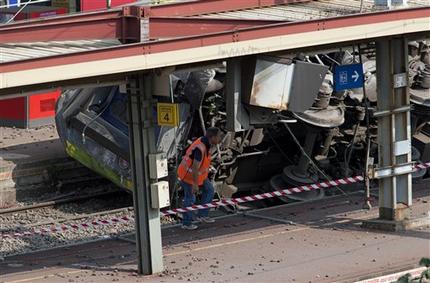 A railway worker walks next to a train which derailed at a station in Bretigny-sur-Orge, south of Paris, Saturday, July 13, 2013. An official on Saturday said a faulty rail joint may have caused a train derailment outside Paris that left six people dead and injured dozens. (AP Photo/Thibault Camus)