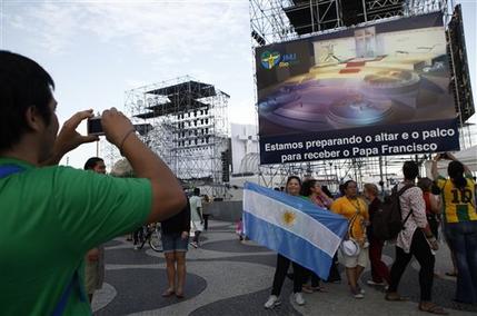 Argentinian pilgrims  takes pictutres in Rio de Janeiro Sunday July 21, 2013, with a giant television monitor erected for the papal visit in the background.    Pope Francis arrives July 22 in  Rio de Janeiro for the World Youth Day.(AP Photo/Jorge Saenz)