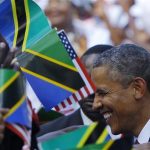 U.S. President Barack Obama is surrounded by Tanzanian and United States flags while greeting people at an official arrival ceremony in Dar Es Salaam July 1, 2013. REUTERS/Gary Cameron