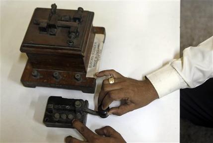 In this Friday, June 14, 2013 photo, a staff member of the central telegraph office shows an old telegraphic equipment which is no longer in use, in Mumbai, India. Just three decades ago - before reliable landlines were laid and well before the age of cheap cellphones arrived - the telegram was king across the vast Indian nation. On Monday, July 15, 2013, the state-run telecommunications company will send its final telegram, closing down a service that fast became a relic in an age of email, reliable land lines and ubiquitous cellphones. (AP Photo/Rajanish Kakade)