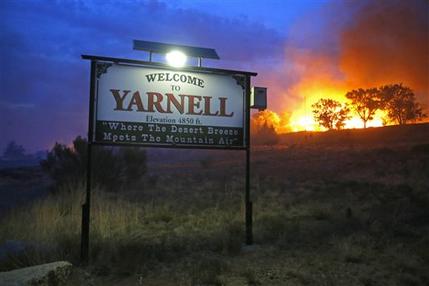 FILE - In this June 30, 2013 file photo, a wildfire burns homes in Yarnell, Ariz. The wildfire that began with a lightning strike and caused little immediate concern because of its remote location and small size quickly blazed into an inferno, leading officials to rapidly order more resources in the hours before flames killed 19 members of an elite Hotshot crew, according to a report released Monday, July 15, 2013. (AP Photo/The Arizona Republic, David Kadlubowski, File)