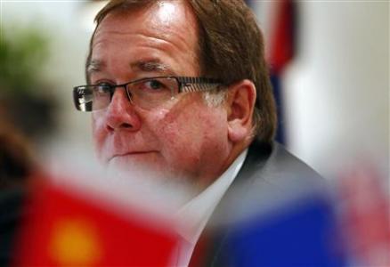 New Zealand Foreign Minister Murray McCully is seen behind Chinese and New Zealand flags during a group interview in Beijing