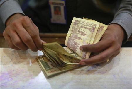 A cashier counts Indian rupee currency notes inside a bank in Mumbai