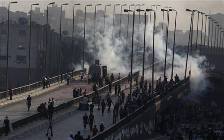 Pro-Mursi supporters flee from tear gas and rubber bullets fired by riot police during clashes in Cairo