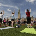 People take part in a free weekly yoga class on the front lawn of Parliament Hill in Ottawa