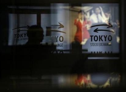 A visitor walks past logos at the TSE in Tokyo