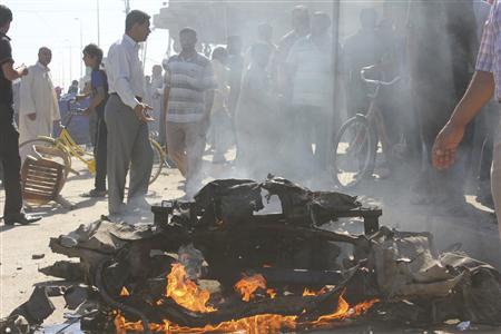 People look at the site of a car bomb attack in Diwaniya