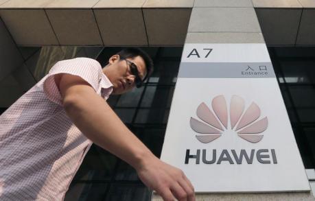 A man walks past a Huawei company logo outside the entrance of a Huawei office in Wuhan, Hubei province