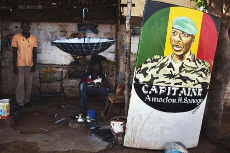 Men sit next to a painting of the ex-junta leader Amadou Haya Sanogo in Bamako