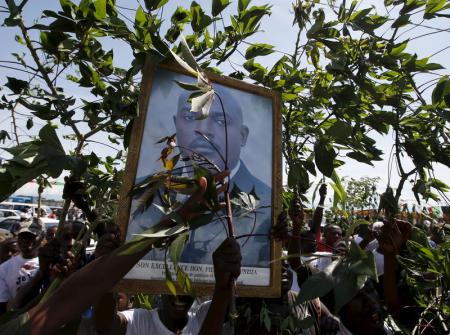 Supporters of Nkurunziza carry his picture as they wait him to return to the capital, at a street in Bujumbura