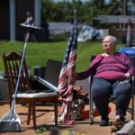 Jackie Moloney, 88, hangs on to her shredded American flag on Monday, May 27, 2024 as her family cleans up on Morningdale Place in Mehlville