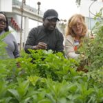 Bella McGowan, right, works at a community garden with local residents Rico De Rixey, center, and his wife Geraldine Brand, Thursday, April 13, 2023, in Los Angeles.