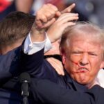 Donald Trump pumps his fist as he is pulled off the stage at a campaign event in Butler, Pa., on July 13, 2024.