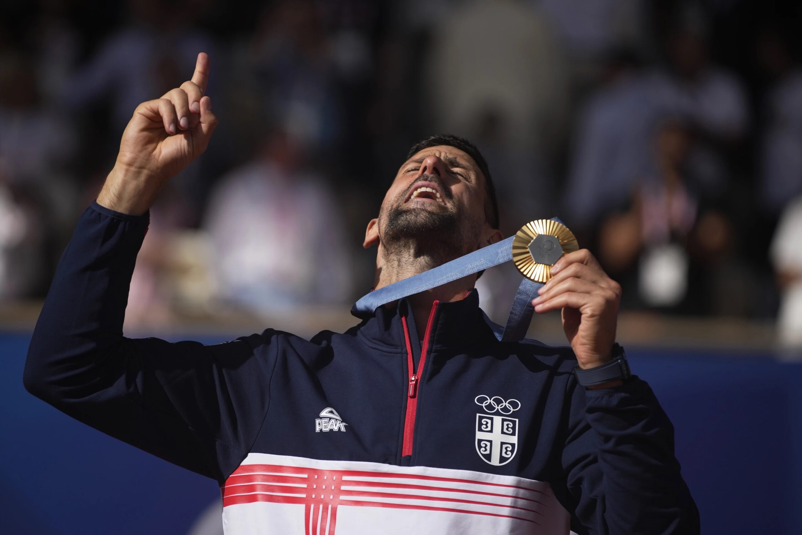 Serbia’s Novak Djokovic shows his gold medal after defeating Spain’s Carlos Alcaraz in the men’s singles tennis final at the Roland Garros stadium during the 2024 Summer Olympics, Sunday, Aug. 4, 2024