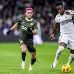 Girona’s Yan Couto, left, duels for the ball with Real Madrid’s Vinicius Junior during a Spanish La Liga soccer match between Real Madrid and Girona at the Santiago Bernabeu stadium in Madrid