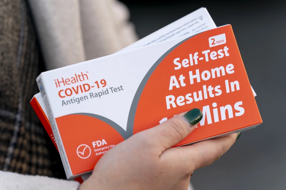 A woman holds two boxes of at-home Covid-19 test kits in Washington, Dec. 22, 2021.