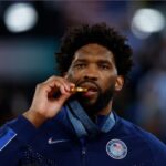 Paris 2024 Olympics - Basketball - Men's Victory Ceremony - Bercy Arena, Paris, France - August 10, 2024. Gold medallist Joel Embiid of United States bites his medal.