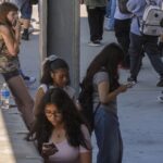 Students use their cellphones as they leave for the day the Ramon C. Cortines School of Visual and Performing Arts High School in downtown Los Angeles, Aug. 13, 2024.