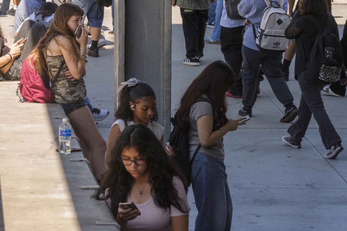 Students use their cellphones as they leave for the day the Ramon C. Cortines School of Visual and Performing Arts High School in downtown Los Angeles, Aug. 13, 2024. 