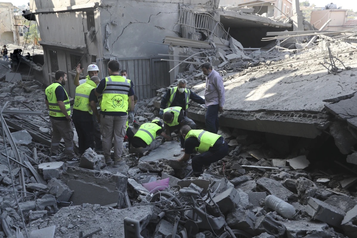 Rescue workers remove rubble, as they search for victims at the site that was hit by Israeli airstrikes in Qana village, south Lebanon, Wednesday, Oct. 16, 2024.