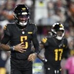 Washington Commanders quarterback Jayden Daniels (5) winces in pain after a play in the second half of an NFL football game against the Chicago Bears Sunday, Oct. 27, 2024, in Landover, Md.