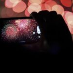 A spectator records a cell phone video as fireworks are launched over the Ohio River during the Western & Southern WEBN Fireworks show in Cincinnati on Sept. 3, 2023, in Cincinnati.