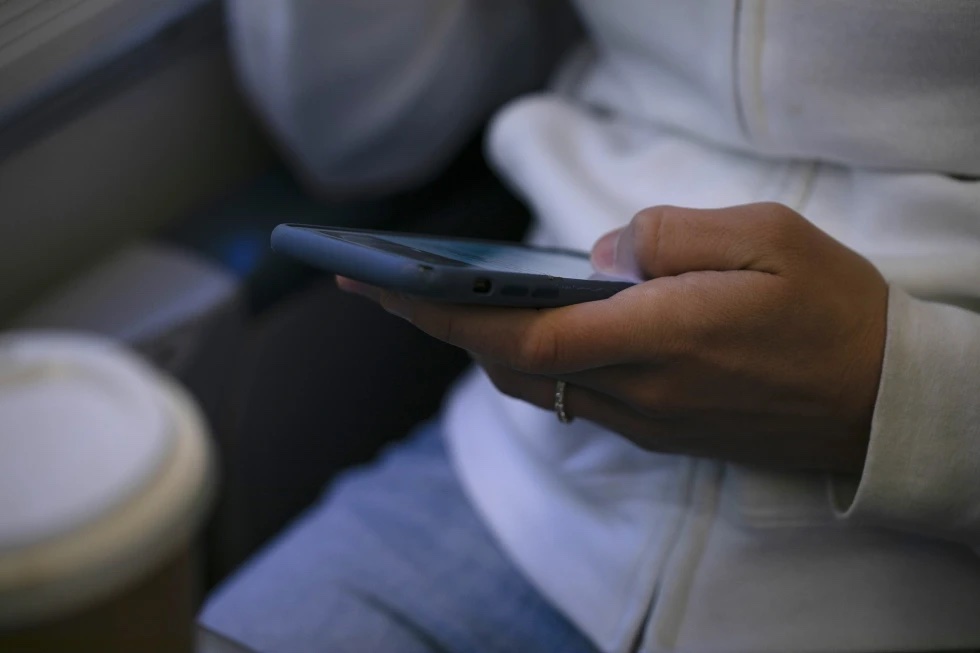 A woman looks at a hand held device on a train in New Jersey on May 18, 2021.