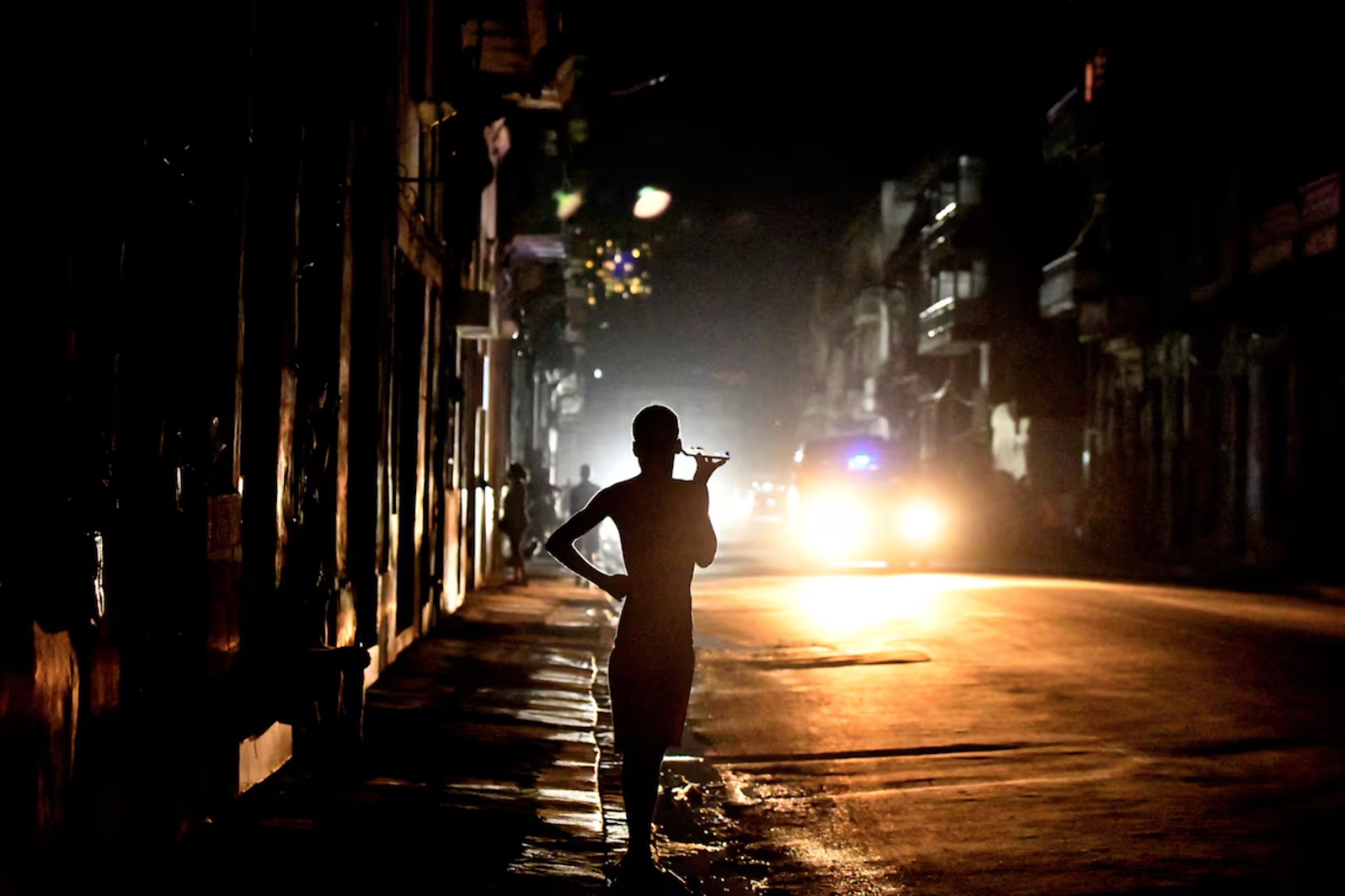 People stand in the street at night as Cuba is hit by an island-wide blackout, in Havana, Cuba, October 18, 2024. 