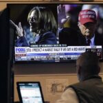 A screen on the floor of the New York Stock Exchange, Monday, Nov. 4, 2024 shows a broadcast talking about Kamala Harris and Donald Trump.