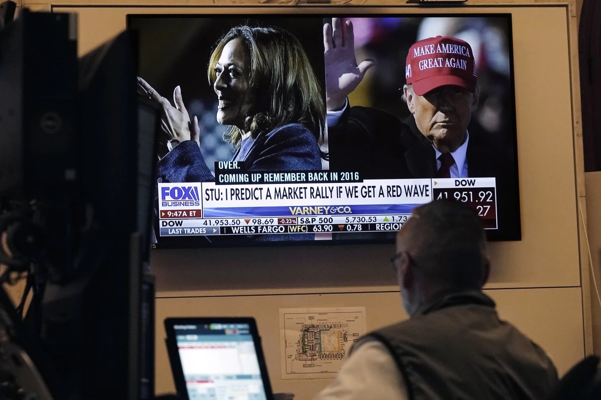 A screen on the floor of the New York Stock Exchange, Monday, Nov. 4, 2024 shows a broadcast talking about Kamala Harris and Donald Trump. 