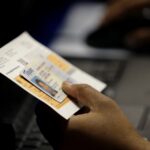 An election official checks a voter’s photo identification at an early voting polling site in Austin, Texas, Feb. 26, 2014.