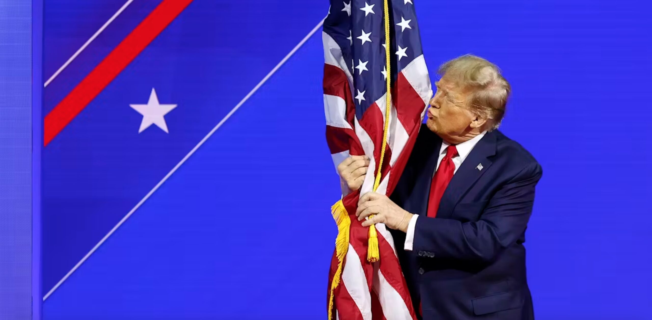 Donald Trump hugs an American flag as he arrives at the Conservative Political Action Conference on Feb. 24, 2024, in Baltimore. 