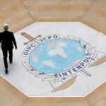 People walk on the Interpol logo at the international police agency headquarters in Lyon, France, on Nov. 8, 2018.